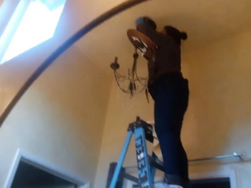 Electrician installing a chandelier in a Monte Sereno residence